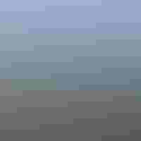 A blue sky above an expansive marsh with green marsh grass and tidal creeks